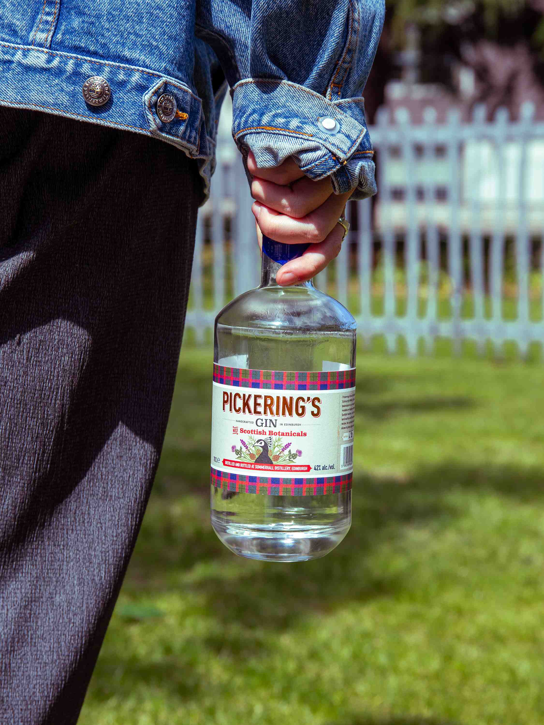 Person holding a bottle of Pickering's Gin with a garden background