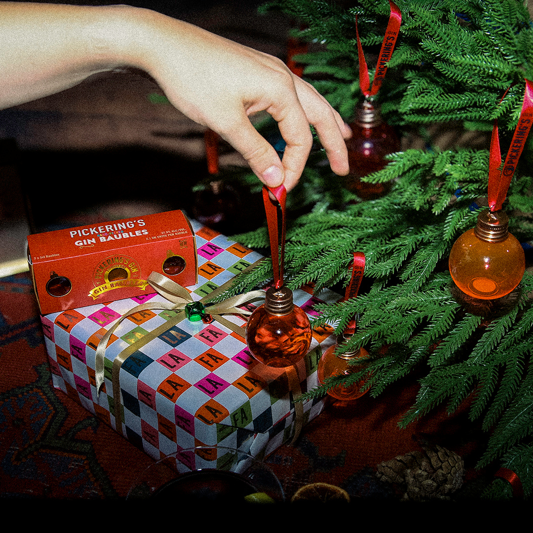 Someone holding a Pickering's Gin Bauble near a Christmas Tree