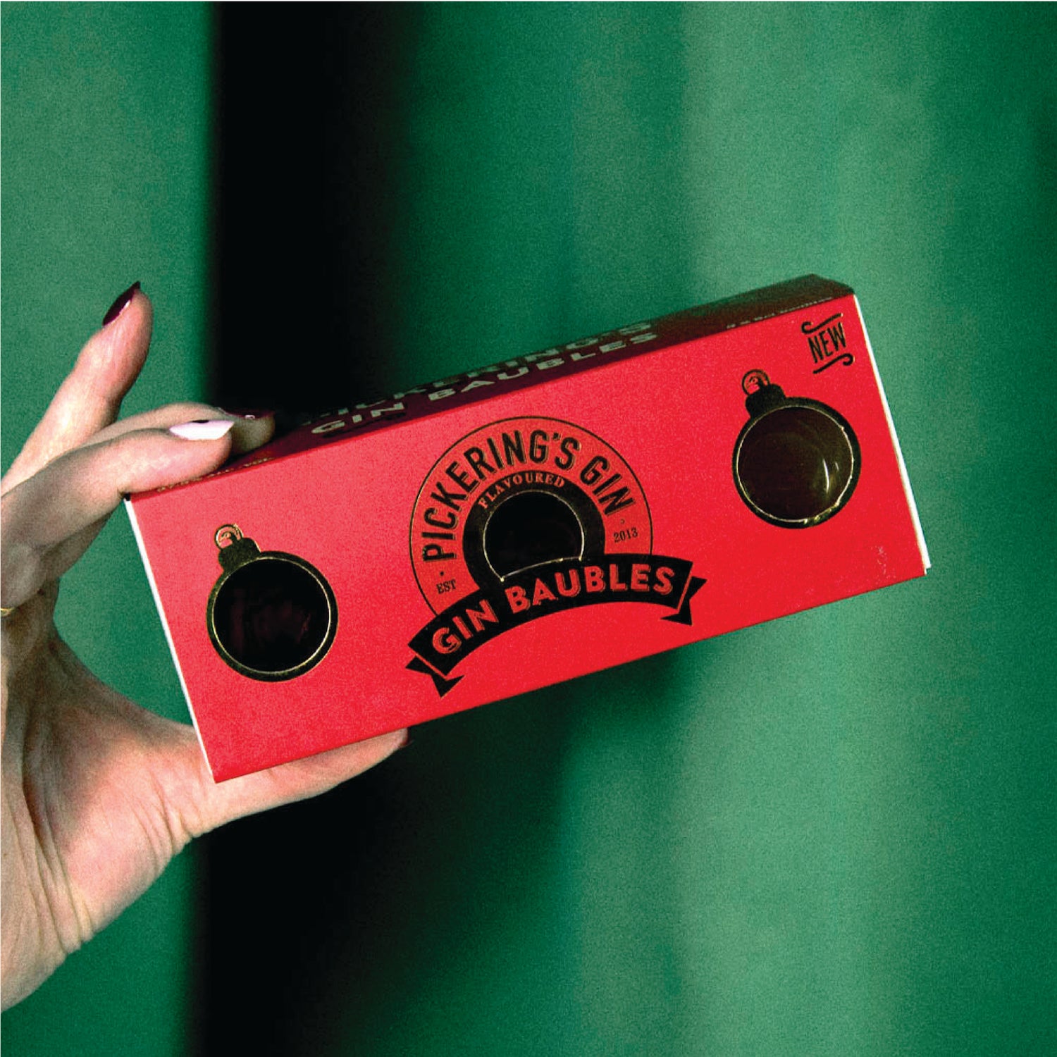 Someone holding a pack of Pickering's Gin Baubles on a green background